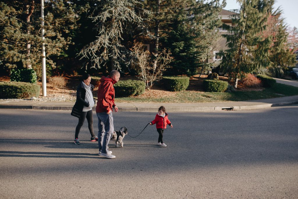 family walking small dog in neighborhood